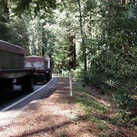 A truck barely stays inside the line while rounding the curve between mile post markers 1.35 and 1.40. The area on the right is where Caltrans proposes a “sliver fill.”  Photo by David Bergin.