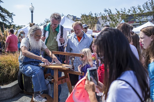 A woodworker demonstrates his hand crafted pedal scroll saw for a crowd at the North County Fair. - ALEXANDER WOODARD