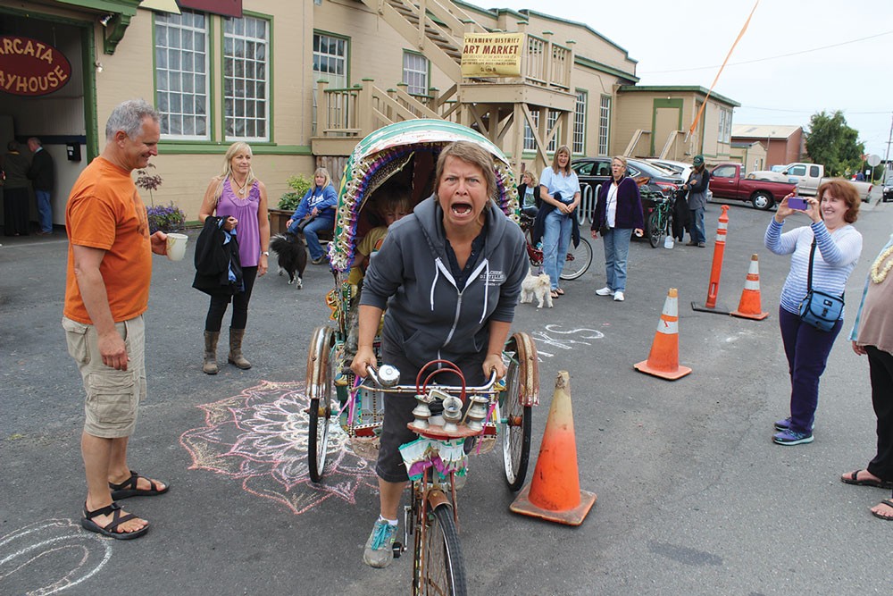 At the new Creamery District Art Market held Saturday, May 31, Jackie Dandeneau of the Arcata Playhouse makes way on her Indian pedicab while market coordinator Louis Hoiland looks on. - PHOTO BY BOB DORAN