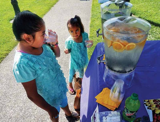 Azuanny and Cynthia guzman sample cool water flavored with fruit comparing it with sugary beverages in a booth for the WIC nutrition program at the Arcata Farmers' Market, Saturday, July 26. - PHOTO BY BOB DORAN.