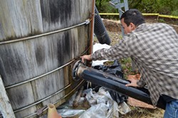 PHOTO BY GRANT SCOTT-GOFORTH - Erick Arcos points out leaks and temporary repairs to Alderpoint's faltering water tanks.