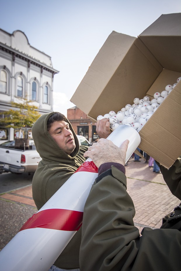 Matt Casagrande of Eureka helps load the ping-pong balls into the "snowball cannon" made by Dean Kruschke. - PHOTO BY MARK LARSON, COURTESY MARK LARSON PHOTOGRAPHY