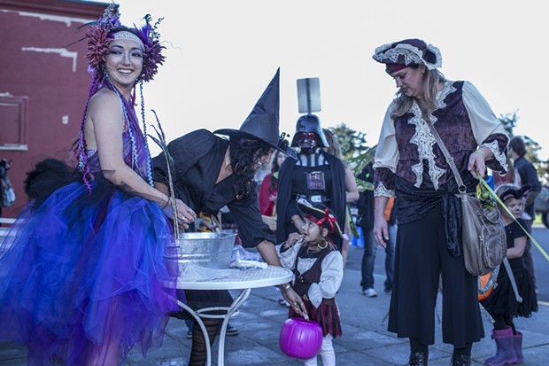 Grace Ivers, left, and Morgan Mireles of Cafe Brio, hand out candy to 2-year-old pirate Lela Aspuria and her mom Jennifer. - ALEXANDER WOODARD