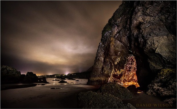 The cave mouth, with the lights of Trinidad and surroundings in the distance. Note the cleft in the rock above the mouth. It is also plainly visible on the inside all the way to be back. It was a cloudy night. I’m usually looking for the Milky Way in a sky, but this cottony substance covering the view had its own charm. - COURTESY OF DAVID WILSON