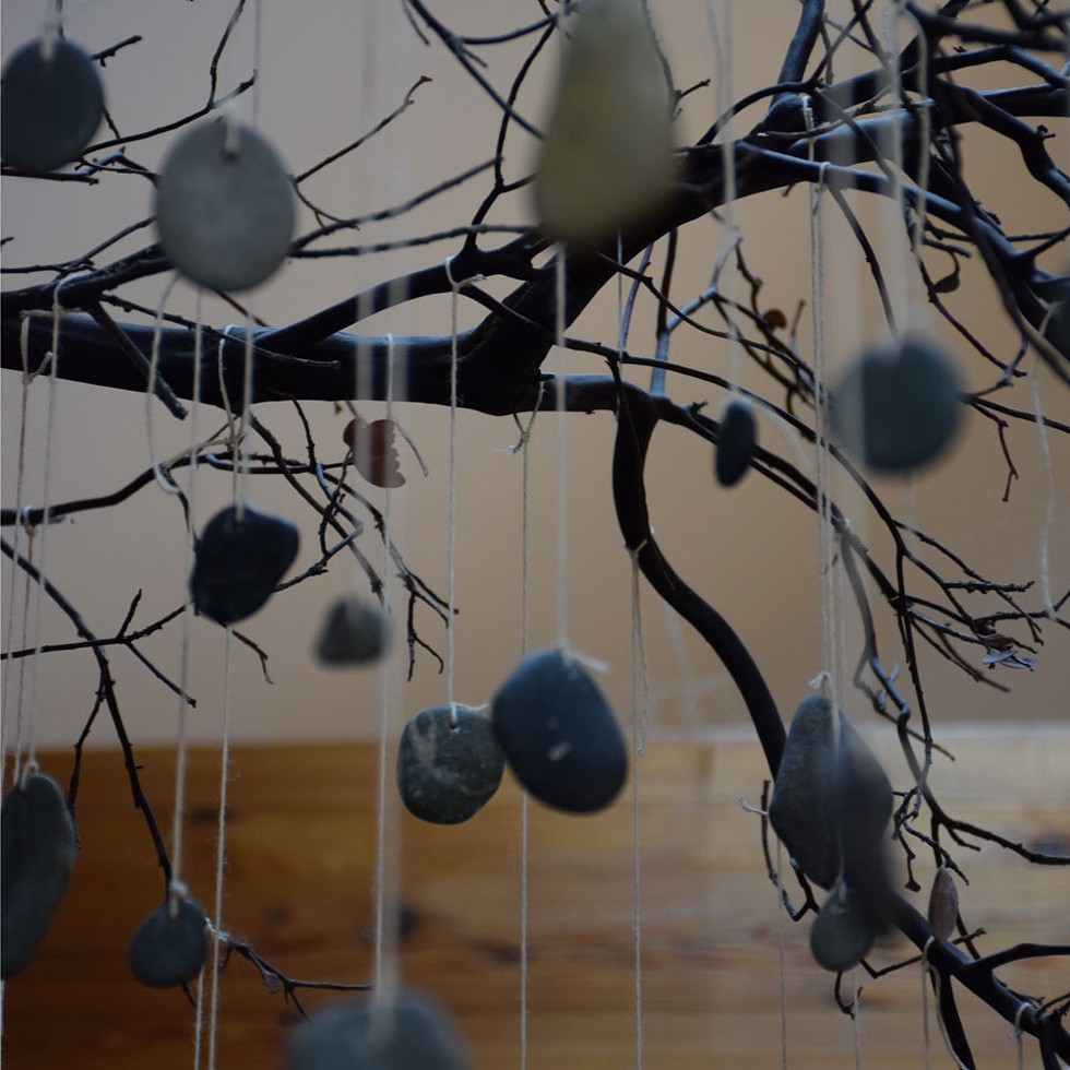 River rocks, each representing a ResolutionCare patient who has died, hang from a Manzanita branch in the health care company's office. - PHOTO BY THADEUS GREENSON