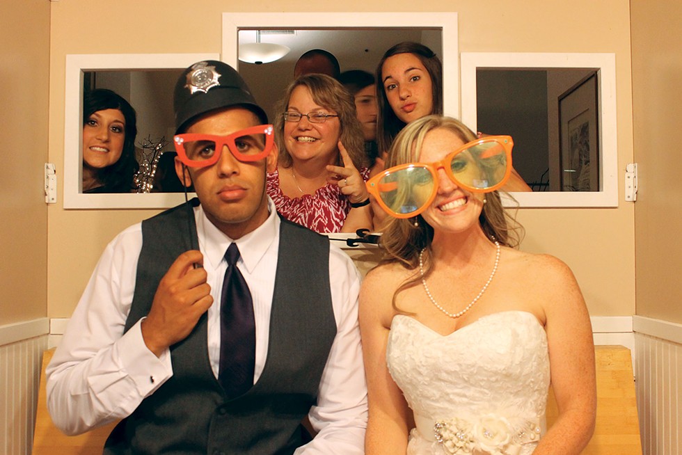 Lyndon and Brittany Powell ham it up in a Sunny Nights photo booth - at their wedding. Guests Ashley Pearce, Carolyn Barnhart and Jenna Barnhart photobomb from behind. - SUNNY NIGHTS PHOTO BOOTH
