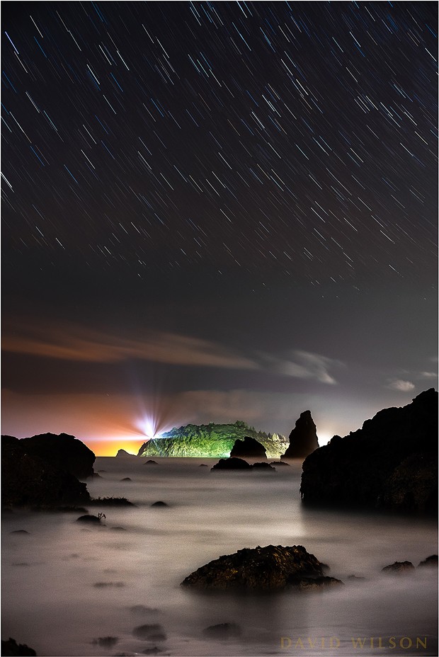 Looking north toward Trinidad and Trinidad Head from Houda Point Beach, Humboldt County, California. This is actually a little west of north, as you can see from the arc of the star trails that the North Star, Polaris, would be above and to the right of this view. The star trails closer to the cloud layer appear to break up in places due to being partially obscured at times by the moving clouds. Like a skylight cover the cloud layer slid until the stars were replaced by grey. Same thing happened to my hair. - DAVID WILSON