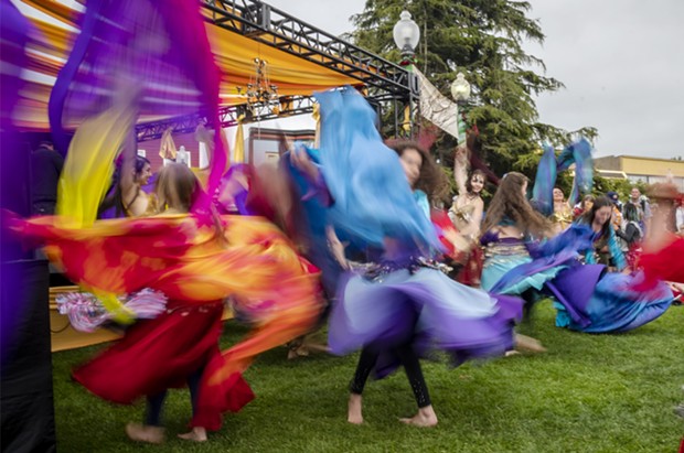 A slow shutter speed allowed the colorful costumes of the belly dancing group Ya Habibi in front the Enchantment Stage to blur in the photo. - PHOTO BY MARK LARSON