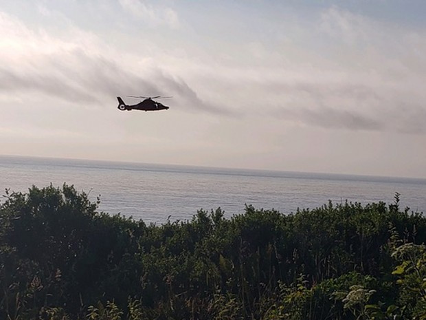 A MH-65 Dolphin helicopter conducts a cliffside rescue after a hiker became stranded near the base of the sea cliff in Patricks Point State Park in Trinidad, California, July 4, 2019. The hiker was hoisted aboard the Dolphin and transported to local emergency medical services with no reported injuries. - U.S. COAST GUARD PHOTO COURTESY OF ARCATA MAD RIVER AMBULANCE SERVICES