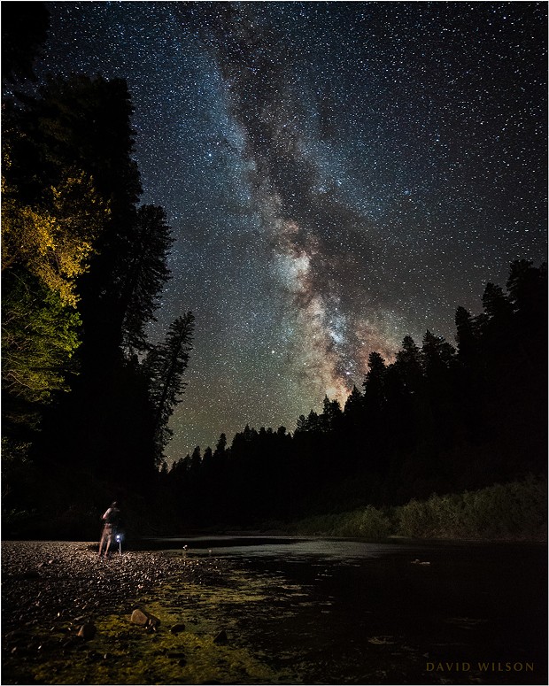 Small beneath the stars, a friend photographs the nightscape on the banks of the South Fork Eel River. Popular in the daytime, we had the site to ourselves. Part of the Milky Way’s core is visible above the horizon, roughly that area with the greater detail and more reds and yellows. Humboldt County, California. - DAVID WILSON