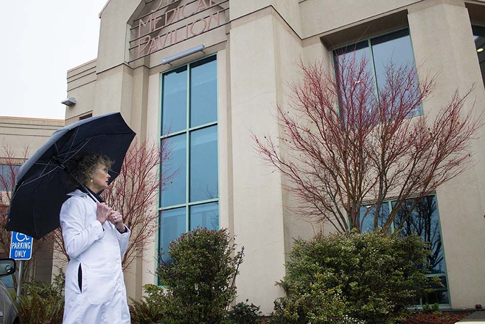Kim Ervin walks by Shaw Medical Pavilion at Mad River Community Hospital on a rainy afternoon. - PHOTO BY THOMAS LAL