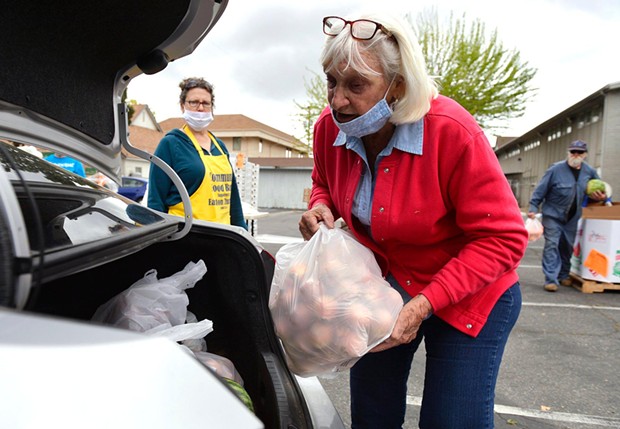 Volunteer Cheryl Phelps, right, helps load food at a food bank giveaway held at Easton Presbyterian Church Monday, April 6, 2020 in Easton. - ERIC PAUL ZAMORA, THE FRESNO BEE
