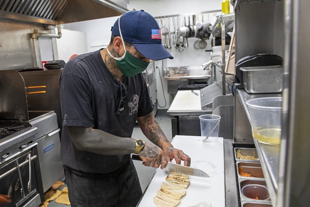 Manzanilla co-owner and sous chef Walter Rubke cuts house made pita for the mezze platter in the kitchen of the newly opened restaurant in Henderson Center. - PHOTO BY MARK MCKENNA