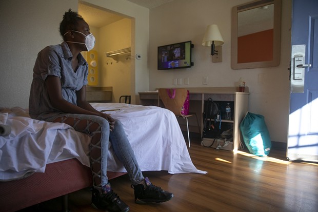 Jamie Burson sits on the bed of her motel room in Farfield on August 4, 2020. Burson, who has been living between her car and motels since being evicted in April, said she feels unsafe at the motel and planned to move again later later that day. - ANNE WERNIKOFF FOR CALMATTERS
