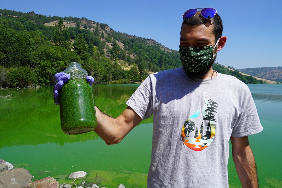 Chris Weinstein, a GIS and drone operator for the Karuk Tribe, holds a jar full of Microcystis cyanobacteria from the Copco Reservoir on the Klamath River. The algae produces a carcinogenic liver toxin called microcystin, which is harmful to humans and animals, including salmon. - STORMY STAATS