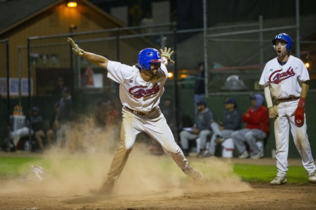 Outfielder Tyler Ganus throws his arms up in a "safe" motion after sliding across home plate to score against the Alaska Goldpanners on August 4, 2021. - THOMAS LAL