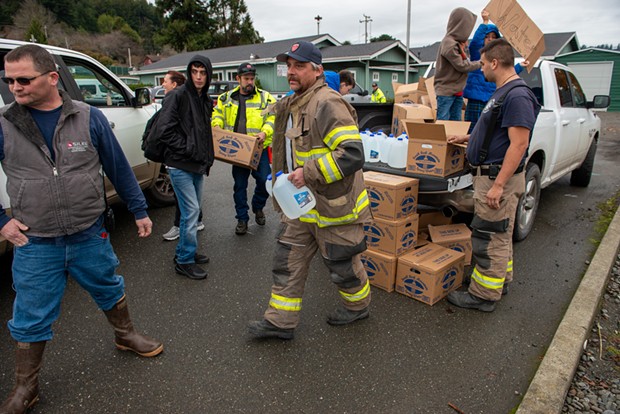 Members of the Rio Dell Volunteer Fire Department hand out water to community members after the city water supply was disrupted by the Dec. 20 quake. - MARK MCKENNA