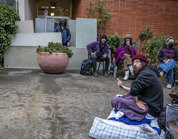 Students sit near the blockaded north entrance of Siemens Hall on Tuesday morning. - MARK LARSON