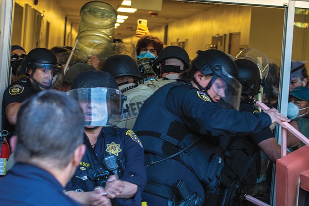 Officers from multiple local police departments attempt to force entry into Siemens Hall to extract protesters on April 22. - PHOTO BY ALEXANDER ANDERSON