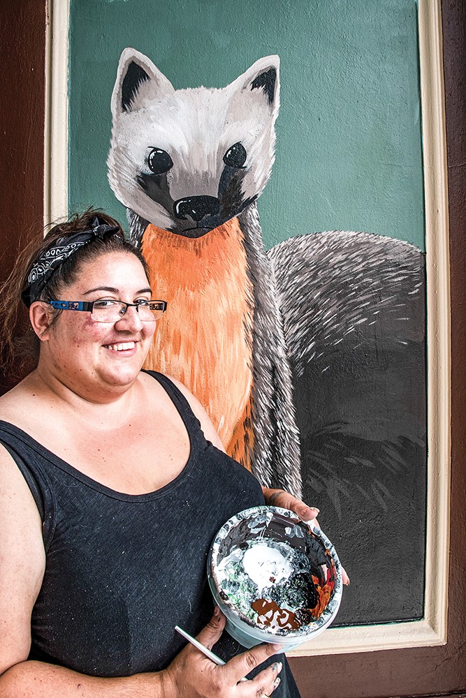 Mural artist Melitta Jackson paused for a moment while painting wildlife murals on the inside side panels of the entrance on the E Street side of the Eureka Municipal Auditorium. - PHOTO BY MARK LARSON