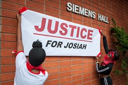 Students hang a "Justice for Josiah" banner on the Humboldt State University quad earlier this month. A similar banner hung outside the D Street Neighborhood Center for the Community Dialogue on Race. - PHOTO BY MARK MCKENNA