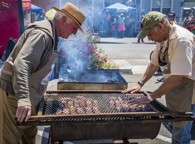 Staffing the barbecue racks filled with coho salmon kept Bruce Wayne (left) and Tim Needham busy. - PHOTO BY MARK LARSON