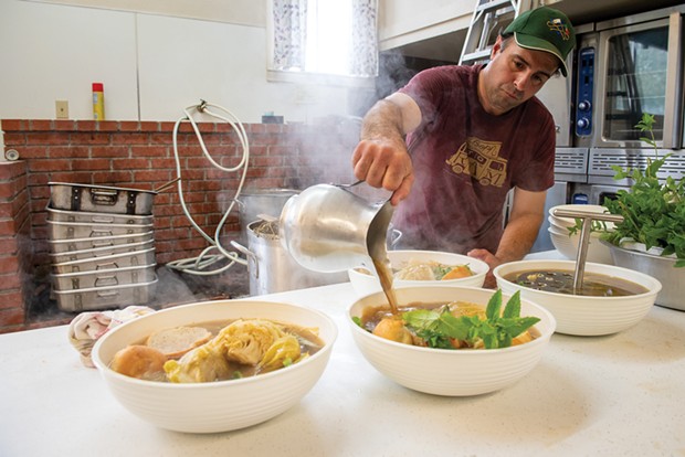 Kevin Oliveira pours the sopas do Espírito Santo broth over the bread and mint.