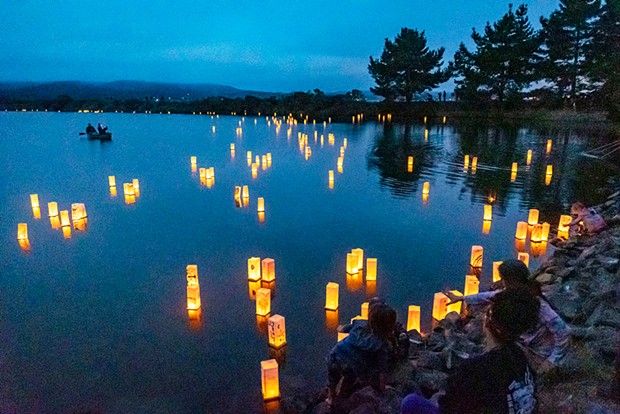 As darkness gathers, participants in the Lighted Lantern Floating Ceremony in August place their personalized lanterns into Klopp Lake at the Arcata Marsh and watch the off-shore breeze push them eastward.