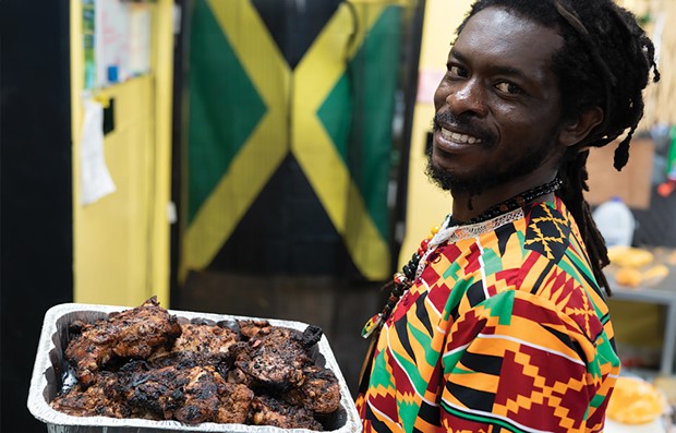Jason Mitchell with a batch of jerk chicken off the grill.