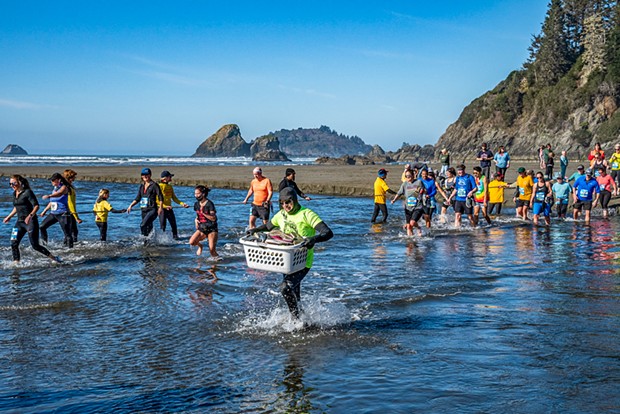 Trinidad to Clam Beach runners crossing Little River as a volunteer shuttles shoes.