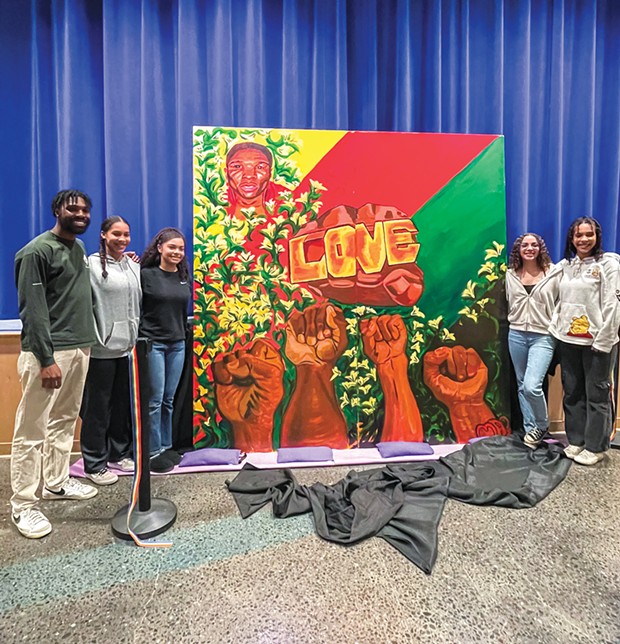 Muralist Malachi Arthur and BSU members Tae Wolford, Aliyah Aaron, Mayleah Jackson and Mae Wolford smile together around the newly unveiled painting of David Josiah Lawson.