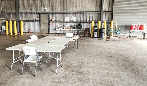A cluster of folding tables serves as both a dining and meeting space in a warehouse at the center of Arcata House Partnership's safe parking program.