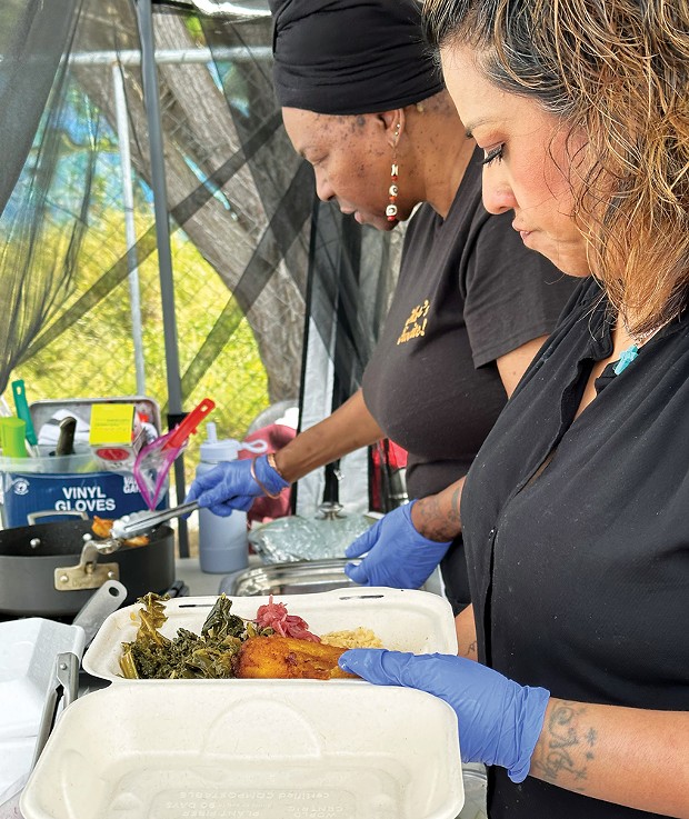 Serving up greens and plantains in the Mother's Cooking Experience stall at the 2023 Juneteenth celebration at Halvorsen Park.