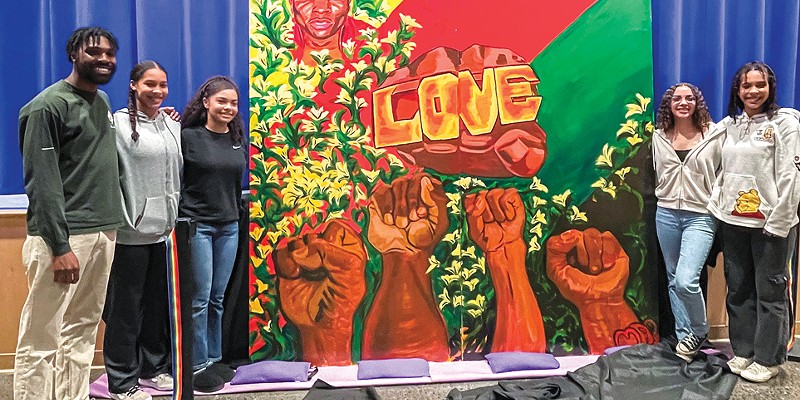 Muralist Malachi Arthur and BSU members Tae Wolford, Aliyah Aaron, Mayleah Jackson and Mae Wolford smile together around the newly unveiled painting of David Josiah Lawson.