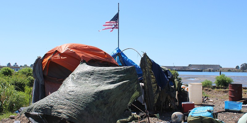 A tattered flag flies over a homeless encampment on the Eureka waterfront.