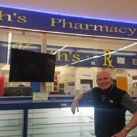 Keith Lorang poses in front of empty shelves at his pharmacy which is closing at the end of Friday.