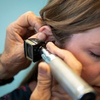A doctor checks a patient's ear for infection at a clinic in Bieber on July 23, 2019.
