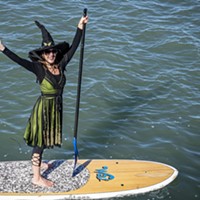 A cheerful witch with a butterfly pin in her hat waved to friends along the Eureka Boardwalk along Humboldt Bay.