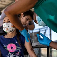 Amaya Palestino, 6, receives a COVID-9 vaccine from assistant Domonic Flowers at one of St. John’s Well Child and Family Center mobile health clinics outside of Helen Keller Elementary School in Los Angeles on March 16, 2022.