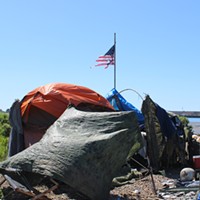 A tattered flag flies over a homeless encampment on the Eureka waterfront.
