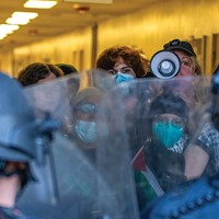 A masked protester inside Siemens Hall yells into a megaphone at officers, demanding they leave the scene on April 22.