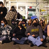 Protesters sit outside the barricaded entrance of Siemens Hall, interlocking arms, on April 22, in an effort to prevent officers from attempting to enter the building.