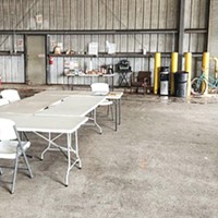 A cluster of folding tables serves as both a dining and meeting space in a warehouse at the center of Arcata House Partnership's safe parking program.