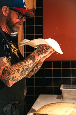 PHOTO BY AOIFE MOLONEY - Shawn Stoops tosses a pizza to be baked in the wood fire oven.