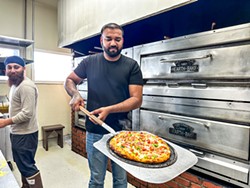 PHOTO BY JENNIFER FUMIKO CAHILL - Garry Bhullar takes a tandoori chicken pizza from the oven.