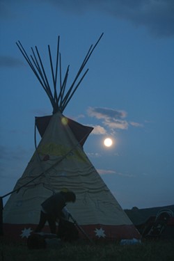 PHOTO BY ALLIE HOSTLER - Just before dinner, the moon rose over the Oceti Sakowin Camp. Singers and drummers could be heard throughout camp as others rushed to cover their camps with tarps to prepare for rain.
